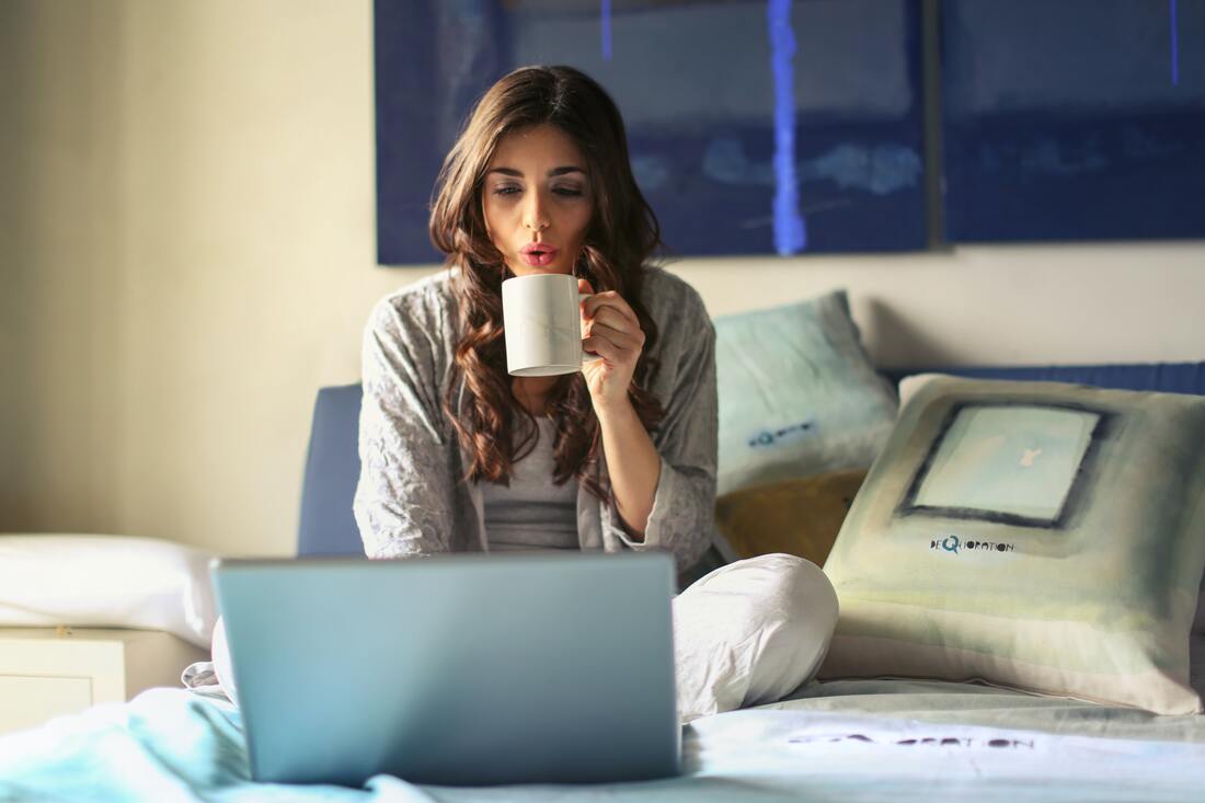 woman sitting on her bed working on laptop